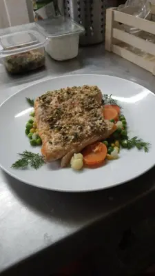 a white plate with fish and vegetables on a table at Hotel FAMIL - adults only in Bansko