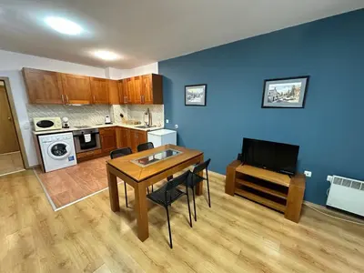 a living room with a table and a kitchen at Pirin place private apartment in Bansko