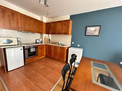 a kitchen with wooden cabinets and a table with a keyboard at Pirin place private apartment in Bansko