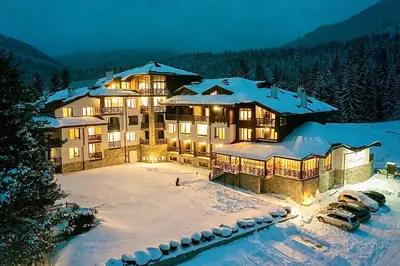 a large building in the snow with cars parked at Smolyan Lakes Apartment / Апартамент Смолянски езера in Smolyan