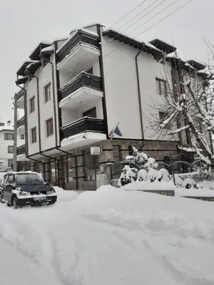 a house with a car parked in the snow at St. Anastasia Apartments in Bansko