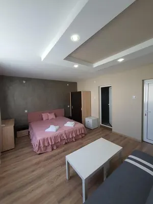 a bedroom with a pink bed and a table at Дамяновата къща in Sapareva Banya