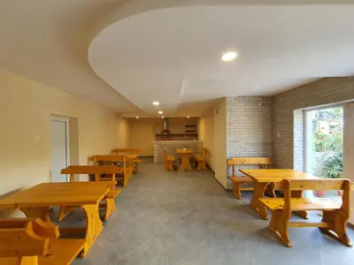 a restaurant with wooden tables and benches and a kitchen at Дамяновата къща in Sapareva Banya