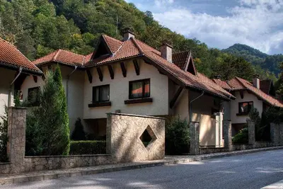 a house on the side of a road next to a mountain at Балкан вили in Ribarica