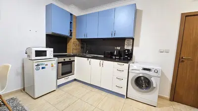 a kitchen with blue cabinets and a washing machine at Апартамент Amare, Гранд Манастира in Pamporovo