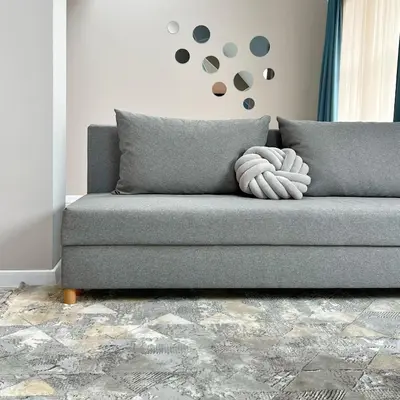 a couch in a living room with a clock on the wall at ATRIUM Boutique Suites Sofia in Sofia