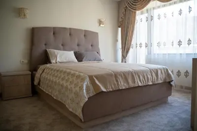 a bedroom with a large bed with a large window at Хотел България Петрич in Petrich