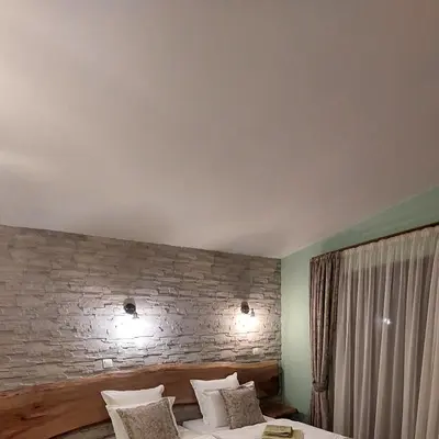 a bedroom with a brick wall and a bed with pillows at Къща за гости Радост Guest House Radost in Razlog