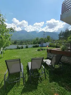 two chairs sitting in the grass in a yard at Къща за гости Радост Guest House Radost in Razlog