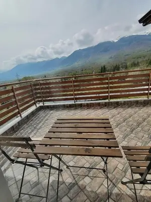a wooden bench with a table and two chairs at Къща за гости Радост Guest House Radost in Razlog