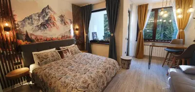 a hotel room with a bed and a desk and windows at FOX boutique apartment Borovets Gardens in Borovets