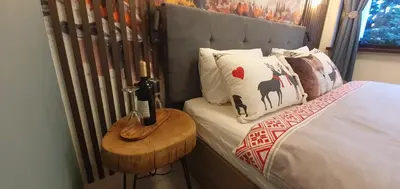 a bed with a side table with a bottle of wine at FOX boutique apartment Borovets Gardens in Borovets