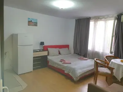 a bedroom with a bed and a table and a refrigerator at Тих двустаен самостоятелен апартамент с двор,до площада на Сандански in Sandanski