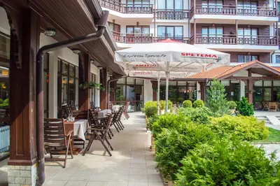 a patio with tables and chairs and an umbrella at Winslow Infinity Aparthotel in Bansko