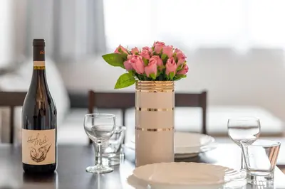 a bottle of wine and a vase with flowers on a table at Sunny 1BDR Apartment near Center in Sofia