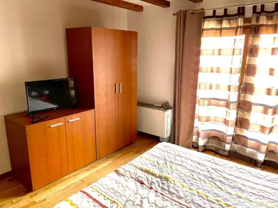 a bedroom with a bed and a cabinet with a television at Апартаменти за гости ,,Friends