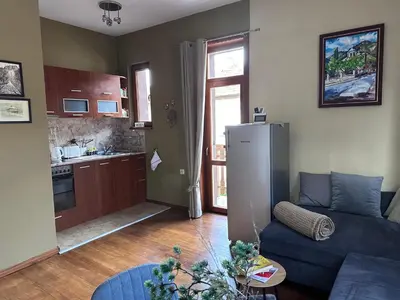 a living room with a blue couch and a kitchen at Апартаменти за гости ,,Friends