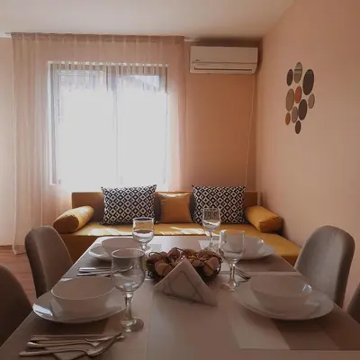 a dining room table with wine glasses and a couch at Апартамент Лидия in Chepelare