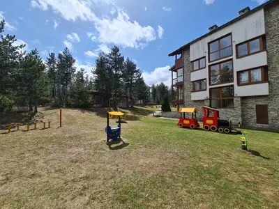 a yard with playground equipment in front of a building at Pirin Golf Apartment HOME with private garden in Bansko