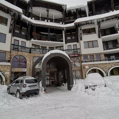 a car parked in the snow in front of a building at Grand Monastery Pamporovo Apartment for rent in Pamporovo