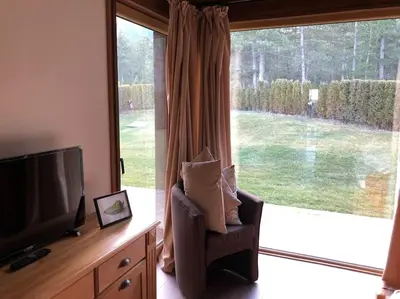 a living room with a tv and a chair and a large window at MAGNET - private chalet in Razlog