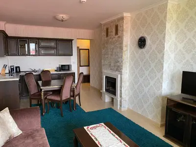 a living room with a table and a kitchen at GrandView Apartment Grand Monastery in Pamporovo