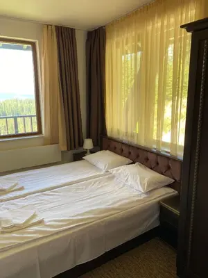 a bedroom with a large white bed with a window at GrandView Apartment Grand Monastery in Pamporovo