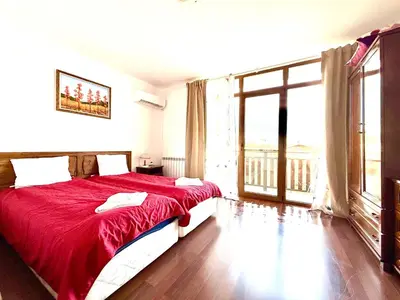 a bedroom with a red bed and a large window at Family Hotel Carpe Diem in Banya