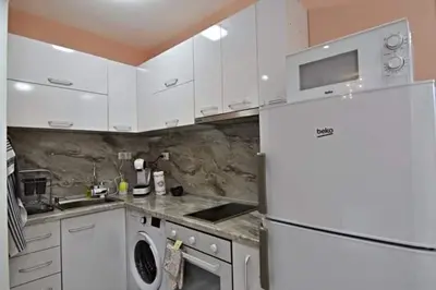 a kitchen with white cabinets and a white refrigerator at Апартамент Фреш in Velingrad