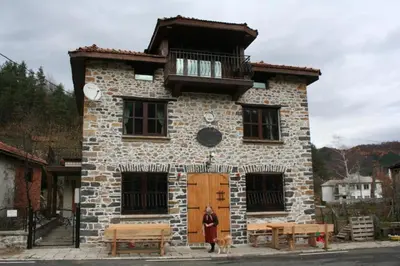 a man standing in front of a building with a dog at Къща Александрова с басейн вътрешен и отопляем in Arda