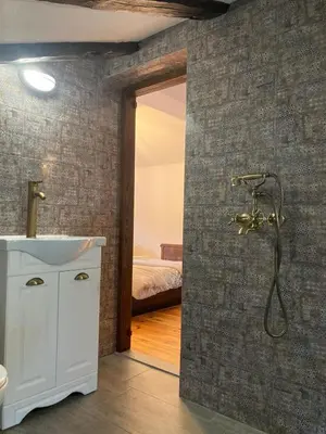 a bathroom with a shower and a sink and a bed at Къща Александрова с басейн вътрешен и отопляем in Arda
