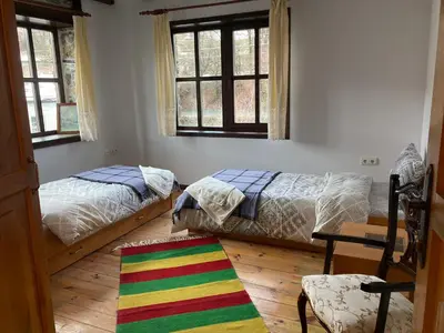 a bedroom with two beds and a colorful rug at Къща Александрова с басейн вътрешен и отопляем in Arda