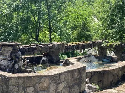 a stone wall with a fountain in a garden at Самостоятелни стаи в къща за гости Балкан in Ribarica