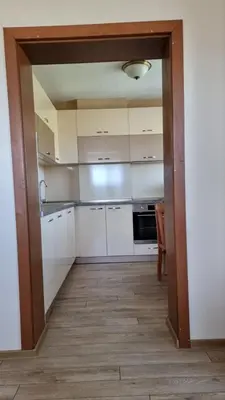 a kitchen with white cabinets and a wooden floor at Родопска къща за гости с.ЧАЛА in Chala