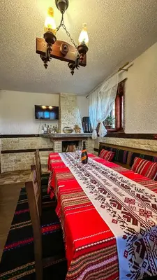 a dining room with a long table with red and white blankets at Родопска къща за гости с.ЧАЛА in Chala
