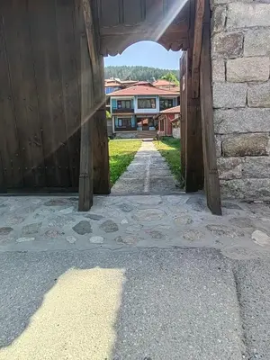 an archway leading into a building with houses in the background at Къща Ради in Koprivshtitsa