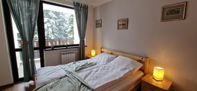 a bedroom with a bed with a window and two lamps at Pine Tree Apartment / Borovets Gardens in Borovets