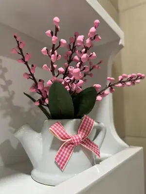 a white vase with pink flowers in it at Georgievi Apartments Sandanski in Sandanski
