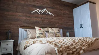 a bedroom with a bed with a wooden wall at House Proctor in Stoykite
