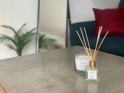 a jar of a candle on a table with bamboo sticks at Minimalist Apartment in Sofia
