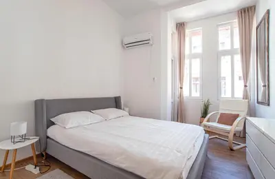 a white bedroom with a bed and a chair at Supreme Luxury Top Central 1 Bedroom Apartment in Sofia
