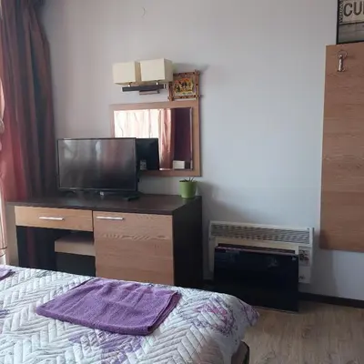 a bedroom with a bed and a dresser with a television at Комплекс Александьр между Банско и село Бяня in Bansko