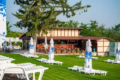 a group of lawn chairs and umbrellas in front of a building at 7 Lakes camping in Sapareva Banya