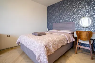 a bedroom with a bed and a mirror and a chair at Amarant Aparts in Sofia