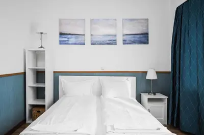 a bedroom with a white bed with three paintings on the wall at Charming Studio on Vitosha Street by Flat Mаnager in Sofia