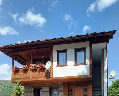 a house with a balcony with flowers on it at Кондеви къщи in Kovachevitsa