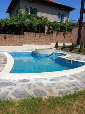 a swimming pool with blue water in front of a house at Guesthouse Gaby in Sapareva Banya