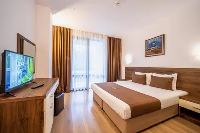 a hotel room with a bed and a flat screen tv at Oak Residence Hotel & Relax in Smolyan