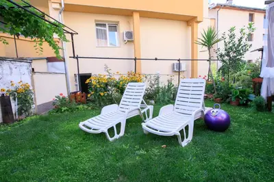 two white chairs sitting in the grass in a yard at Мини Студио Рози in Sandanski