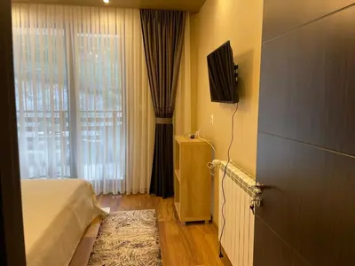 a bedroom with a bed and a television and a window at Апартамент ВАНЕСА in Velingrad